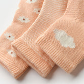 Close-up of Salmon Poppy baby socks with soft texture and embroidered cloud detail